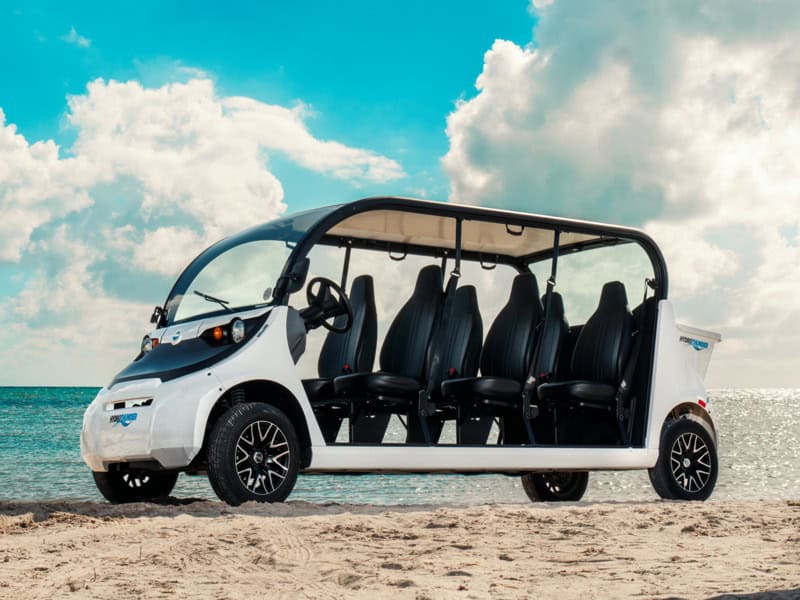 Conch golf cart rental on sandy beach with ocean background and blue sky.